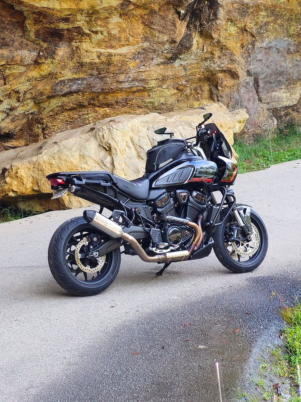 Harley-Davidson Pan America parked by a rock wall with a Stealth Pipes slip-on exhaust, photo 1 of 17
